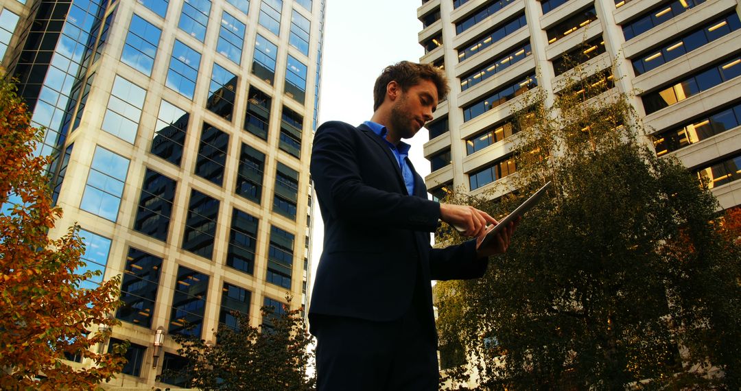 Businessman Using Tablet in Urban Setting with Skyscrapers - Free Images, Stock Photos and Pictures on Pikwizard.com