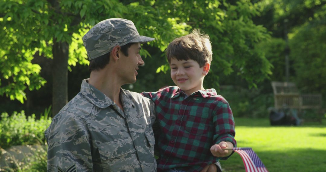 Smiling Soldier with Son Holding USA Flag in Garden