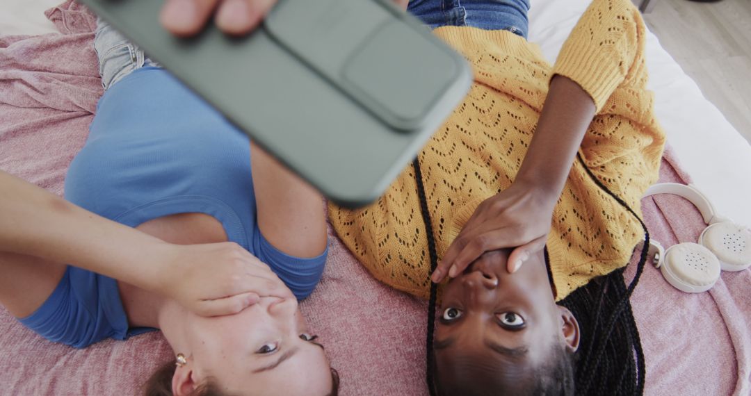 Two Friends Lying Down Taking Selfie with Smartphone - Free Images, Stock Photos and Pictures on Pikwizard.com