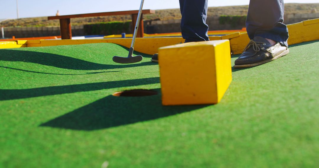 Senior Enjoying Mini Golf Ready to Putt into Hole