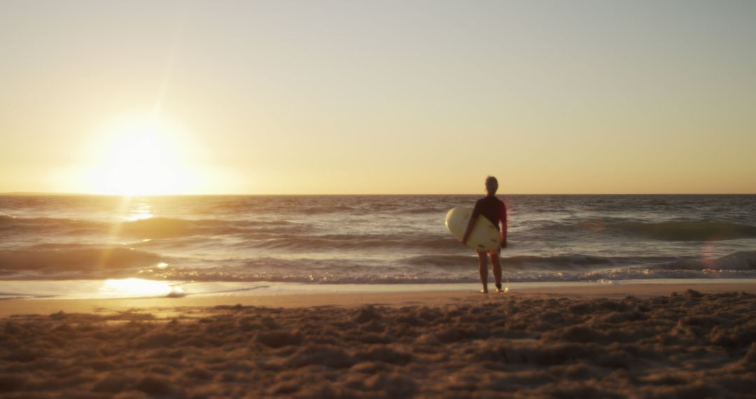 Surfer with Board Watching Sunset on Sandy Beach - Free Images, Stock Photos and Pictures on Pikwizard.com