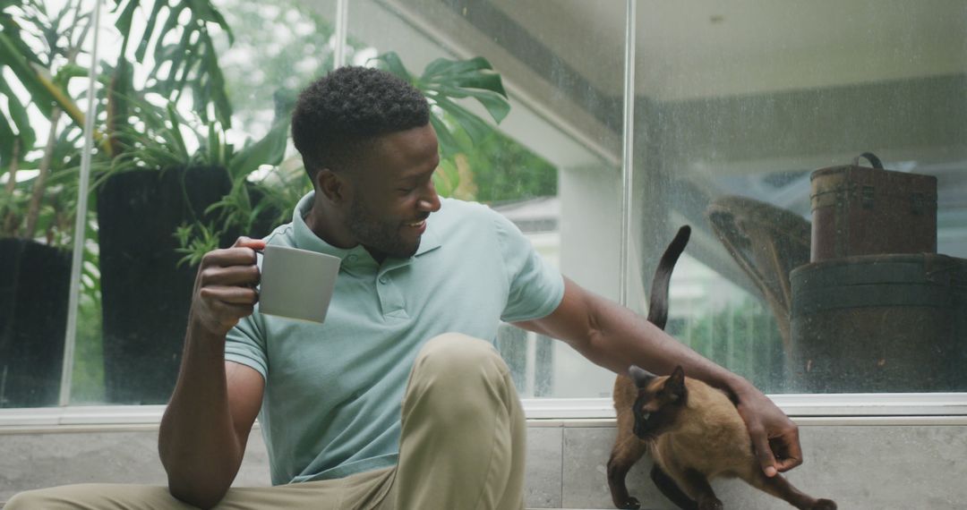 Man Enjoying Morning Coffee with Pet Cat Near Window - Free Images, Stock Photos and Pictures on Pikwizard.com