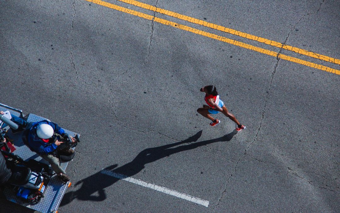 Aerial View of Marathon Runner on Road with Camera Crew - Free Images, Stock Photos and Pictures on Pikwizard.com