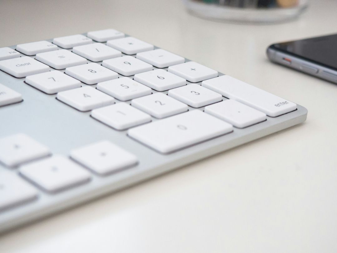Close-up of sleek white keyboard and technology smartphone on desk