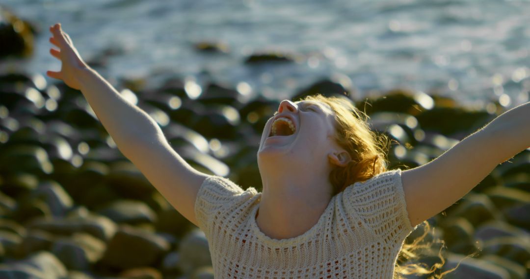 Joyous Woman With Arms Outstretched at Rocky Beach - Free Images, Stock Photos and Pictures on Pikwizard.com