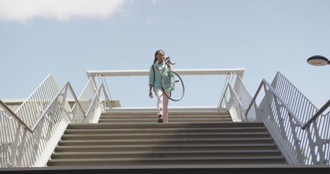 Modern urban woman carrying bicycle up stairs - Free Images, Stock Photos and Pictures on Pikwizard.com