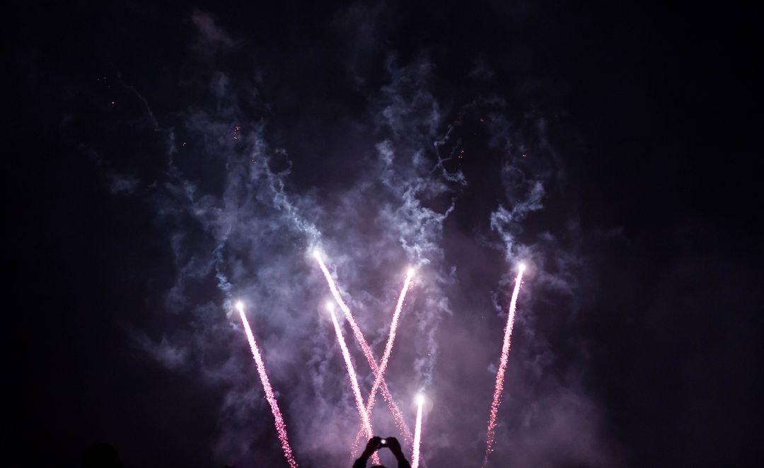 Silhouetted Spectator Capturing Vivid Firework Display Night