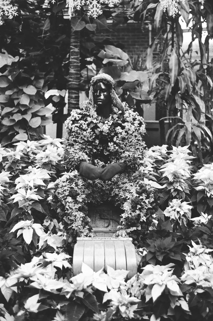 Human statue adorned with flowers in lush garden setting - Free Images, Stock Photos and Pictures on Pikwizard.com