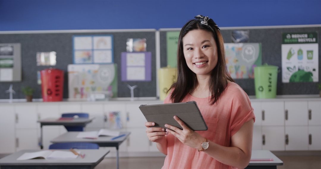 Smiling Asian Female Teacher Using Tablet in Classroom Environment