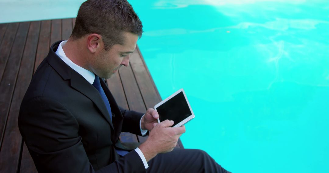 Businessman Working on Tablet by Poolside - Free Images, Stock Photos and Pictures on Pikwizard.com