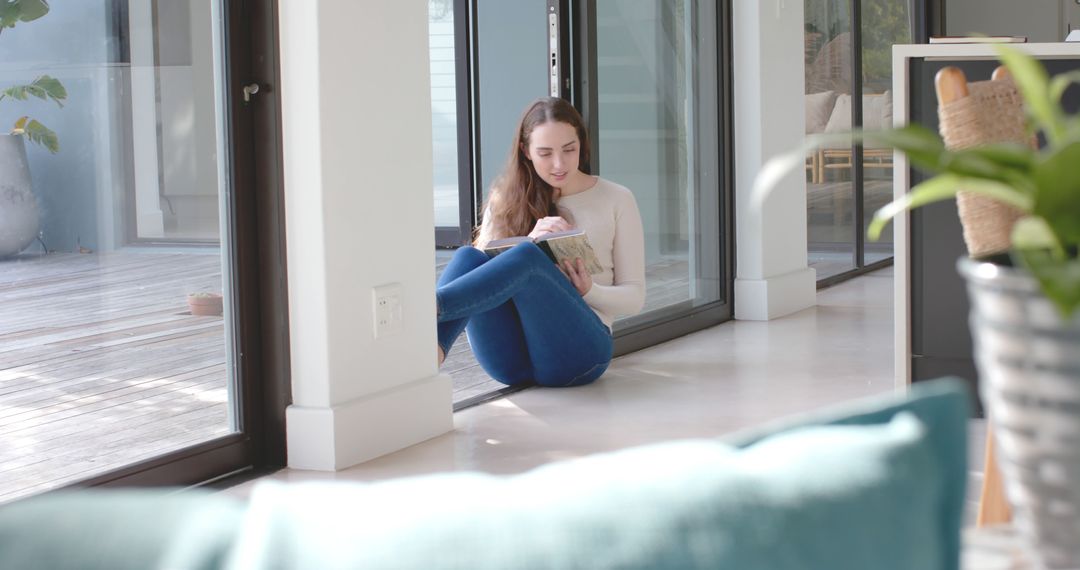 Young Woman Relaxing at Home Reading a Book on the Floor by Windows - Free Images, Stock Photos and Pictures on Pikwizard.com