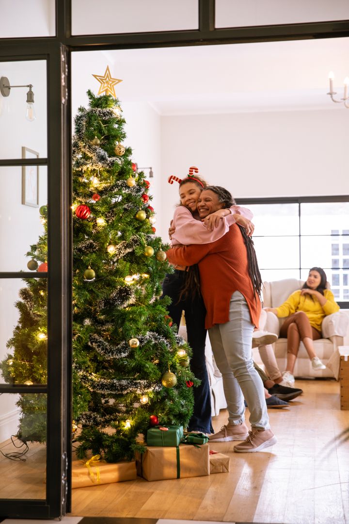 Mother and Daughter Embracing by Decorated Christmas Tree