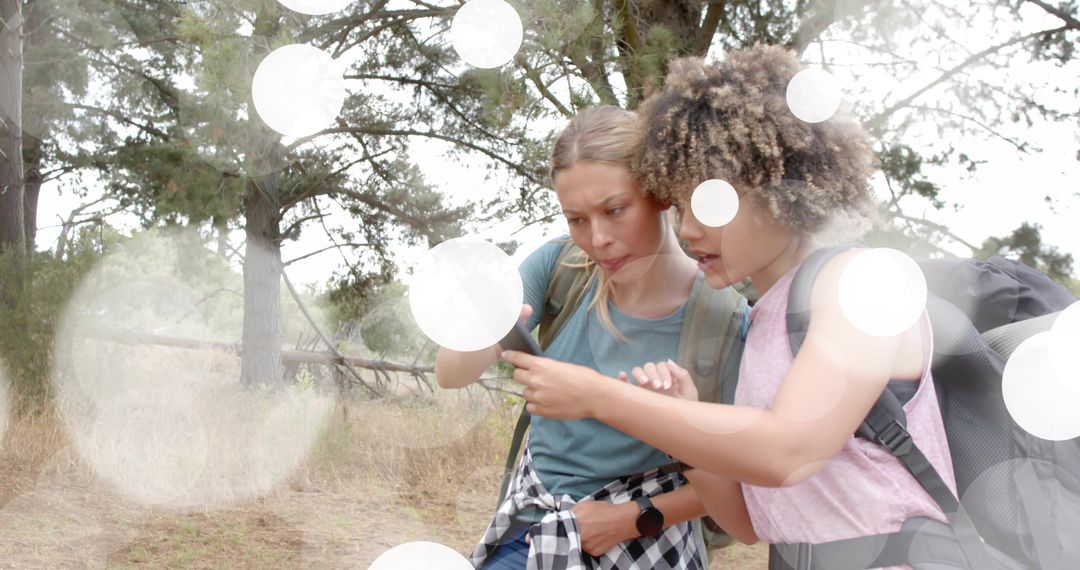 Women Hikers Checking Phone for Navigation on Forest Trail with Backpacks and Smartwatch