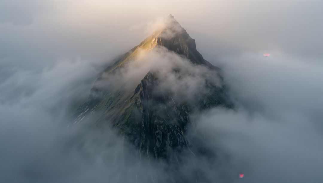 Sharp Alpine Peak Piercing Low Clouds at Dawn, Warm Summit Light and Misty Ridge