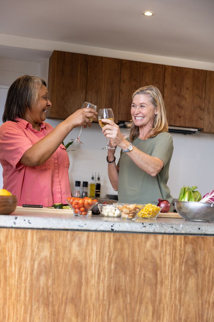 Joyful Female Friends Enjoying Wine and Preparing Salad