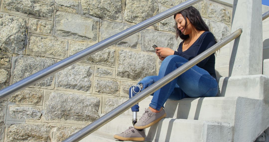 Young Woman with Prosthetic Leg Using Smartphone on Outdoor Steps - Free Images, Stock Photos and Pictures on Pikwizard.com