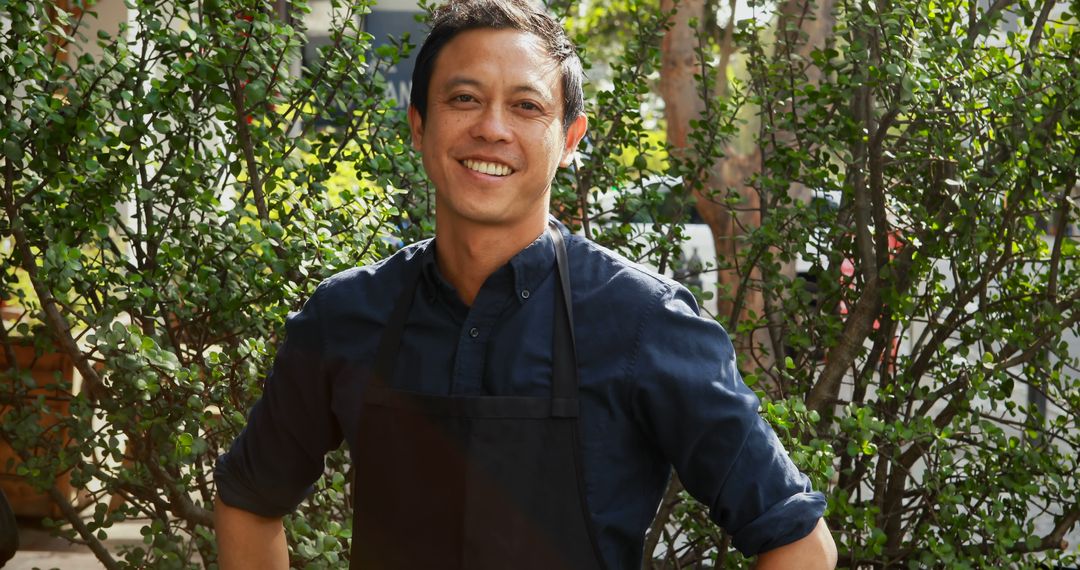 Smiling Male Chef in Black Apron Standing Outdoors - Free Images, Stock Photos and Pictures on Pikwizard.com