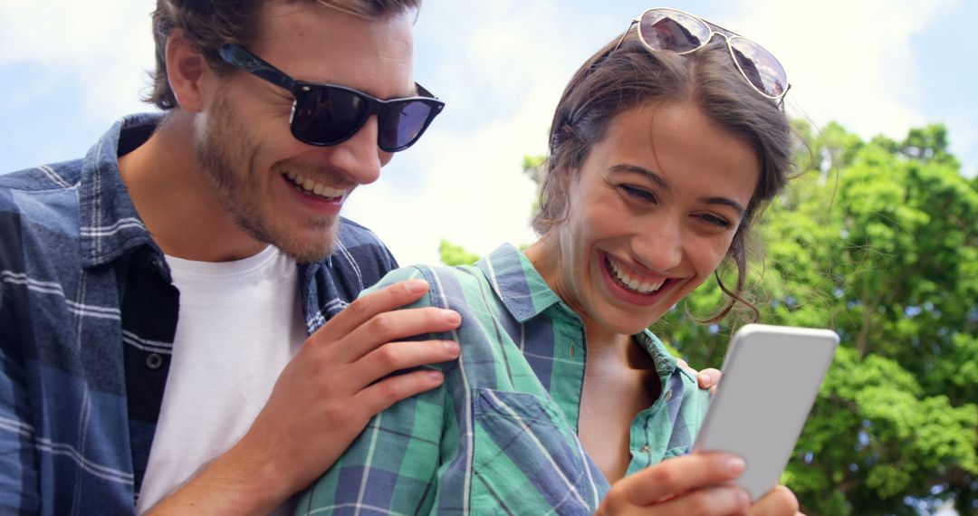 Happy Couple Using Smartphone Outdoors on Sunny Day - Free Images, Stock Photos and Pictures on Pikwizard.com