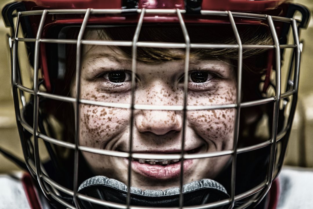 Freckled Child in Hockey Gear Smiling Through Helmet - Free Images, Stock Photos and Pictures on Pikwizard.com