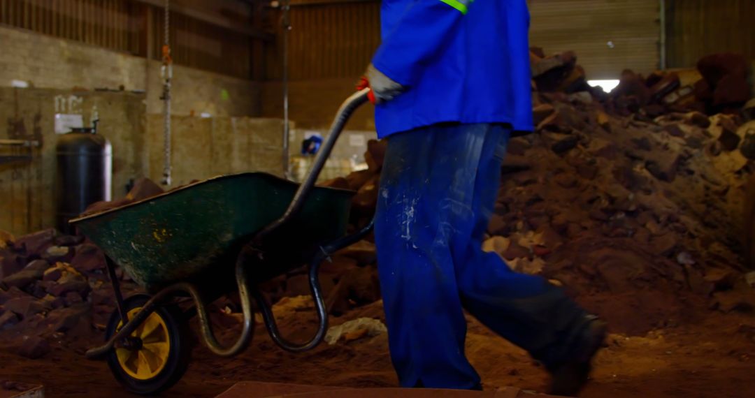 Worker Moving Wheelbarrow in Industrial Warehouse - Free Images, Stock Photos and Pictures on Pikwizard.com