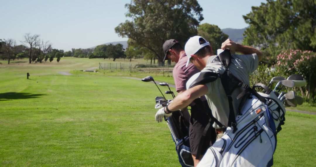 Golfers Carrying Bags on Golf Course on Sunny Day - Free Images, Stock Photos and Pictures on Pikwizard.com