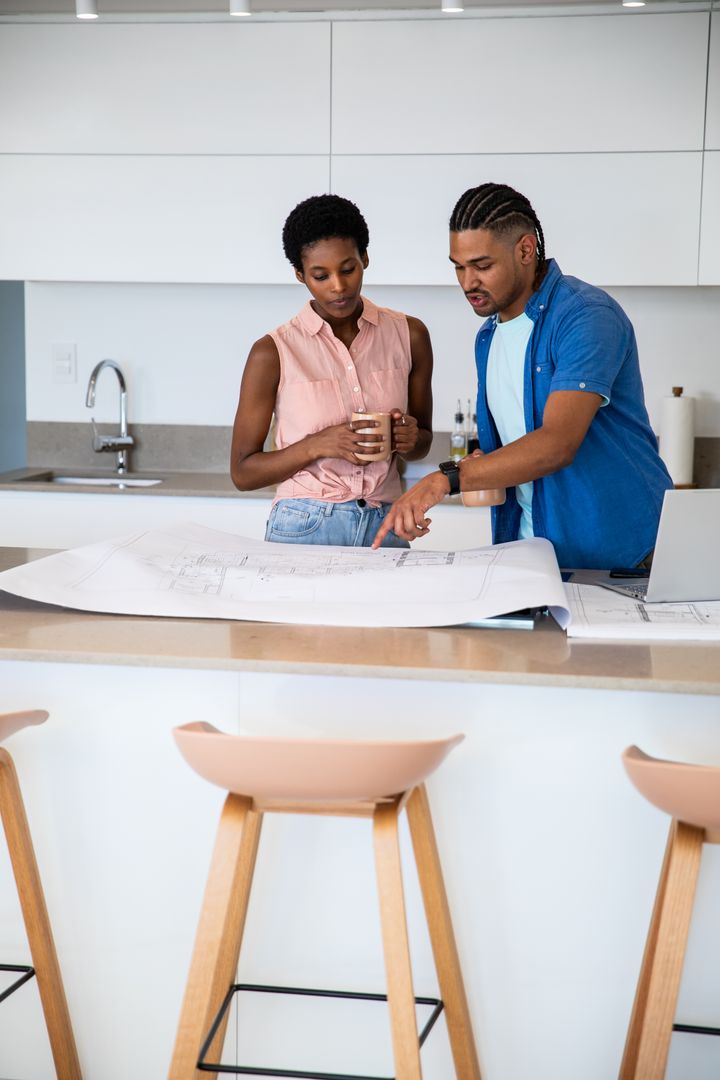 Couple Examining Blueprints in Modern Kitchen for House Design