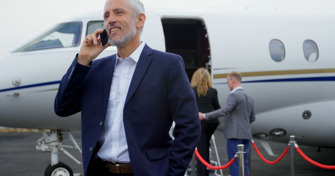 Businessman Talking on Phone Near Private Jet - Free Images, Stock Photos and Pictures on Pikwizard.com