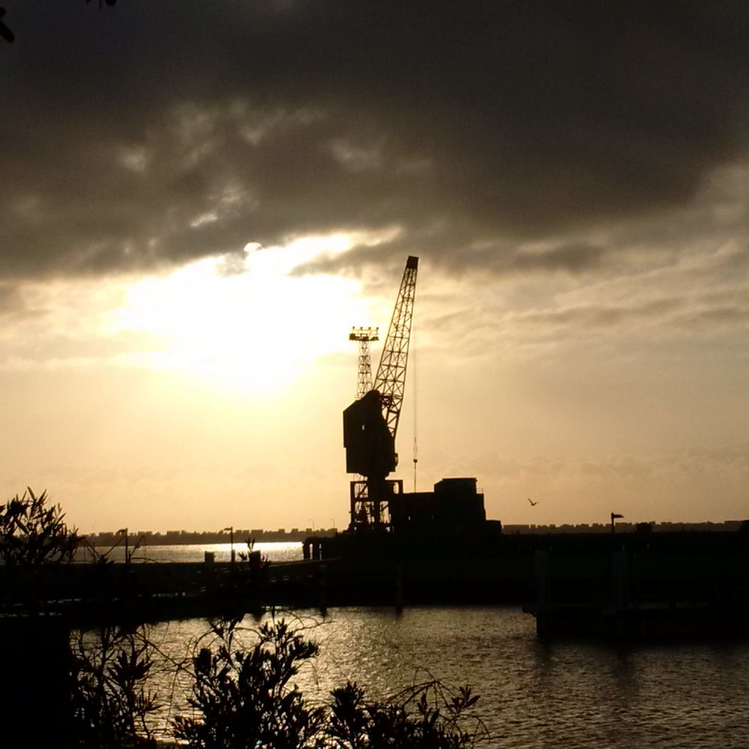 Silhouetted Harbor Crane at Sunset Over Water - Free Images, Stock Photos and Pictures on Pikwizard.com