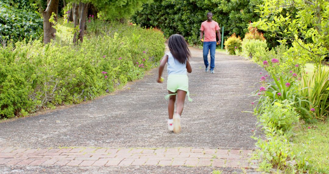 Father Watching Daughter Playing in Sunny Garden