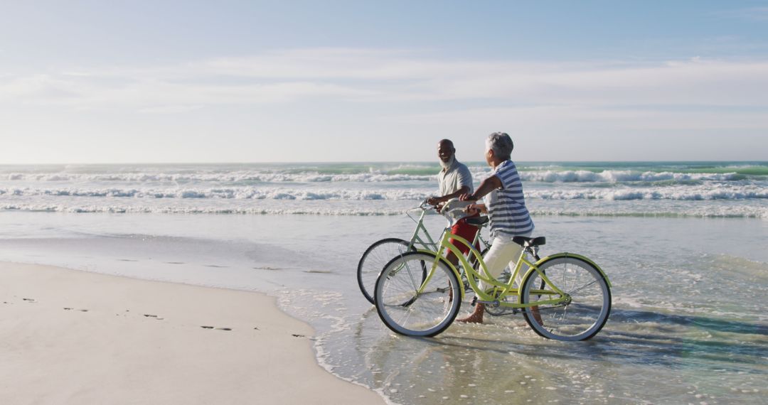 Senior african american couple walking with bicycles at the beach - Free Images, Stock Photos and Pictures on Pikwizard.com