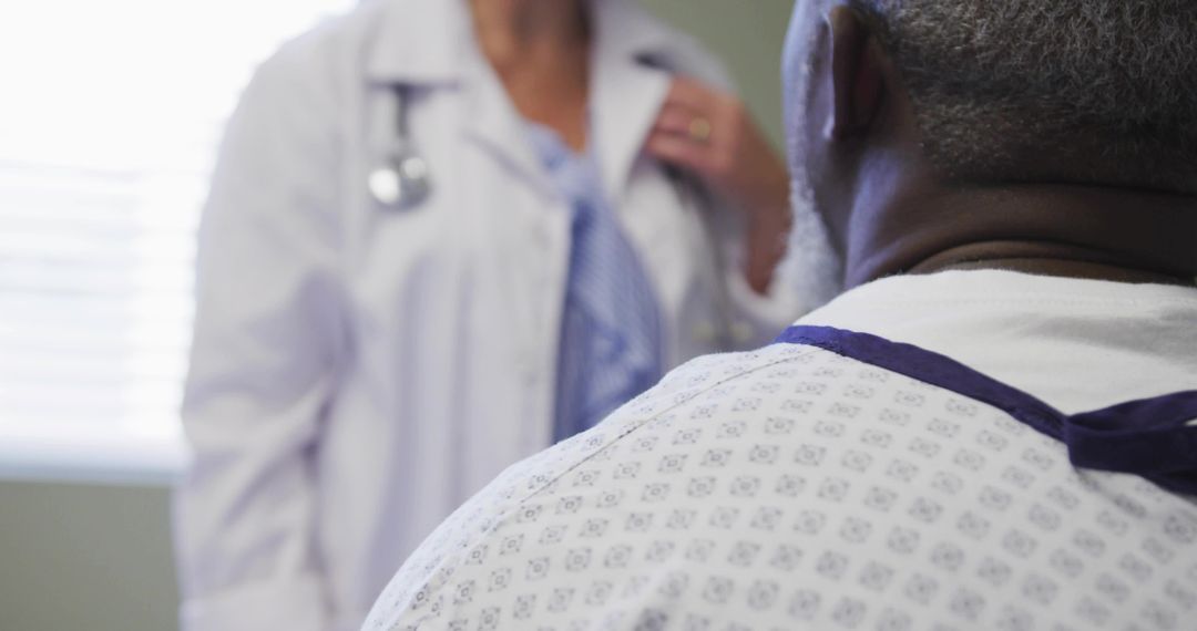 Patient consulting with physician in clinical exam room in gown discussing care plan