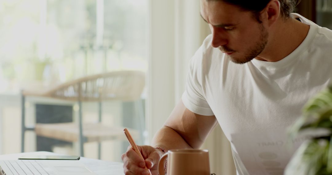Focused Young Man Working Remotely at Home Office Desk