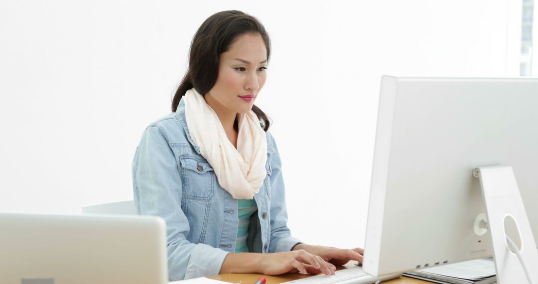 Focused Asian Businesswoman Using Laptop and Desktop in Office