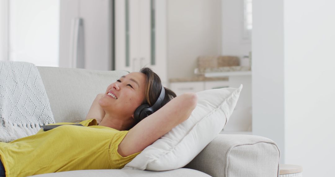 Woman Relaxing on Couch with Headphones in Modern Living Room - Free Images, Stock Photos and Pictures on Pikwizard.com