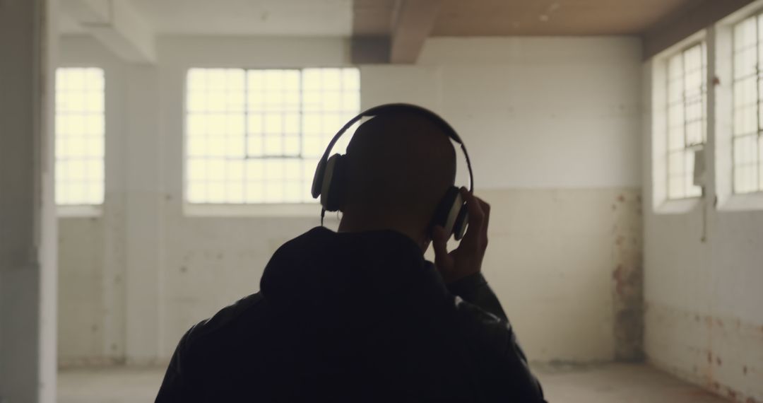 Person Listening to Music on Headphones in Industrial Space - Free Images, Stock Photos and Pictures on Pikwizard.com