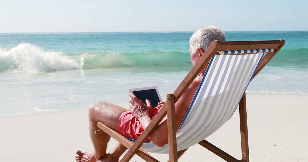 Senior Man Relaxing on Sunny Beach with Tablet - Free Images, Stock Photos and Pictures on Pikwizard.com