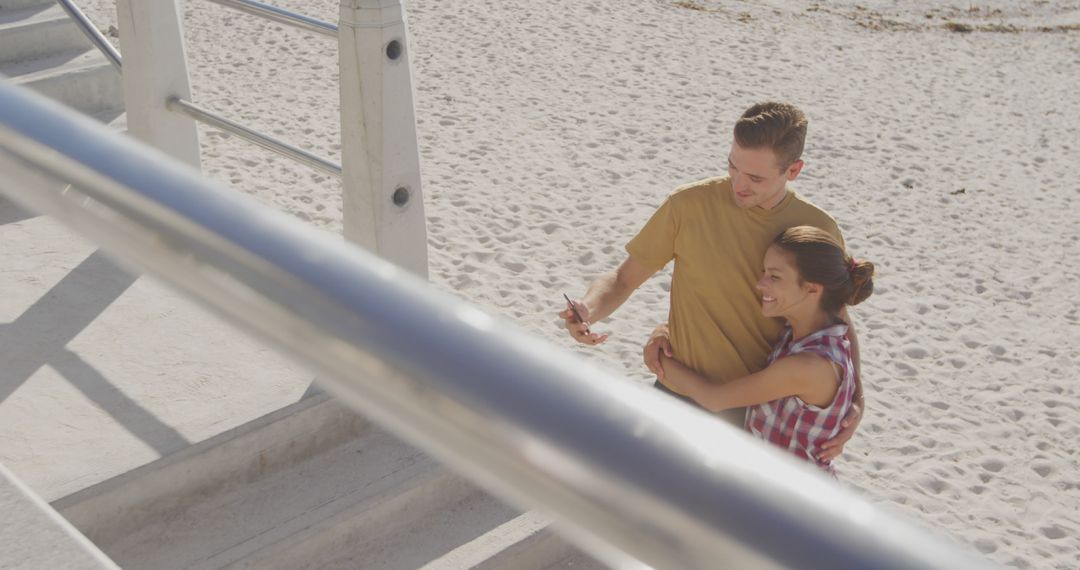 Couple Embracing on Beach While Taking Selfie - Free Images, Stock Photos and Pictures on Pikwizard.com