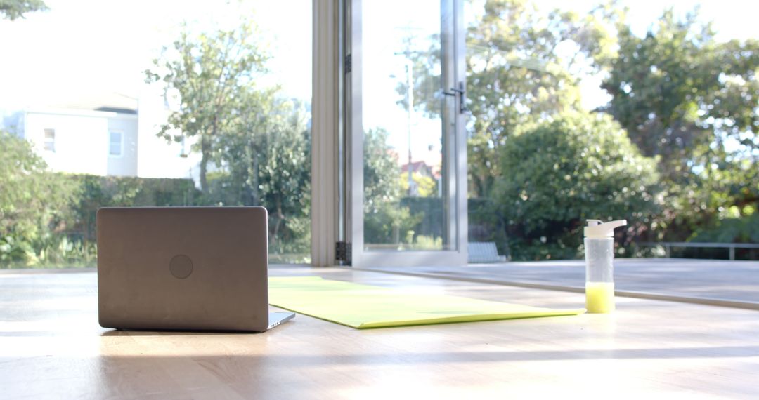 Yoga Mat with Laptop and Water Bottle in Sunny Room - Free Images, Stock Photos and Pictures on Pikwizard.com