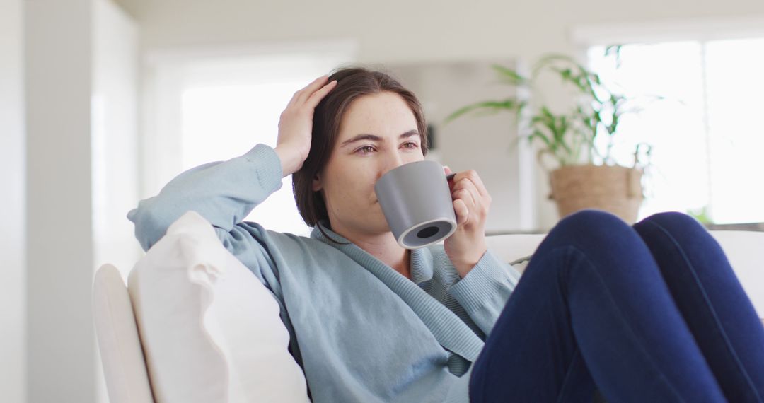 Relaxed Woman Drinking Coffee on Couch in Bright Living Room - Free Images, Stock Photos and Pictures on Pikwizard.com