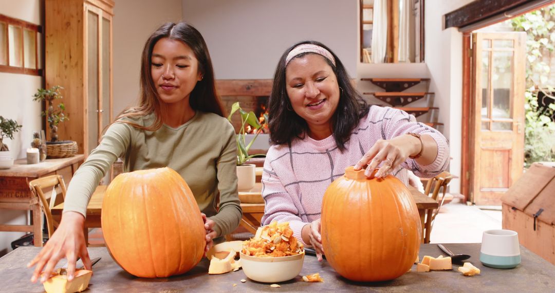 Grandmother and Granddaughter Carving Pumpkins for Halloween at Home