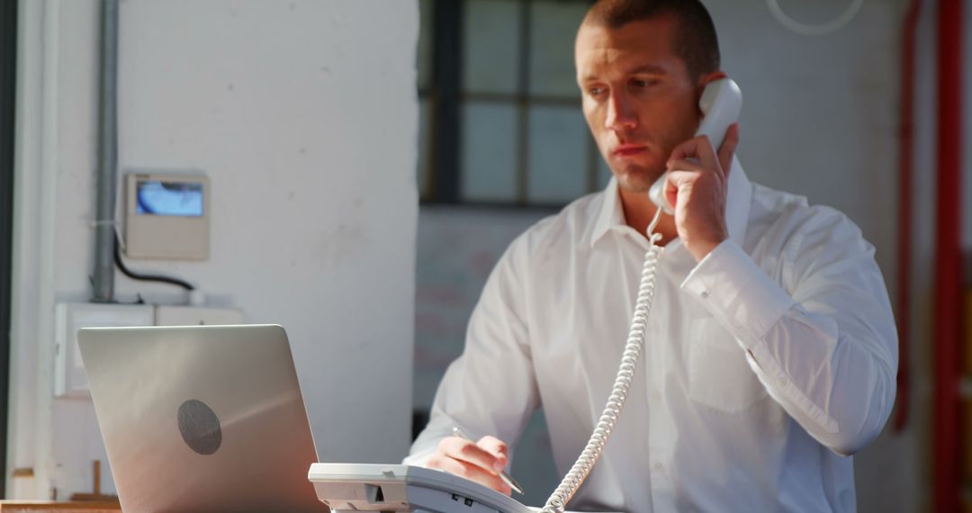 Businessman Taking Notes While Talking on Phone in Office - Free Images, Stock Photos and Pictures on Pikwizard.com