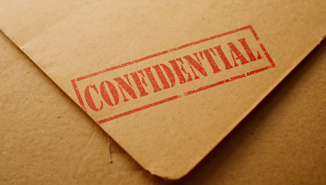 Diagonal kraft envelope with red CONFIDENTIAL stamp on textured cardboard surface