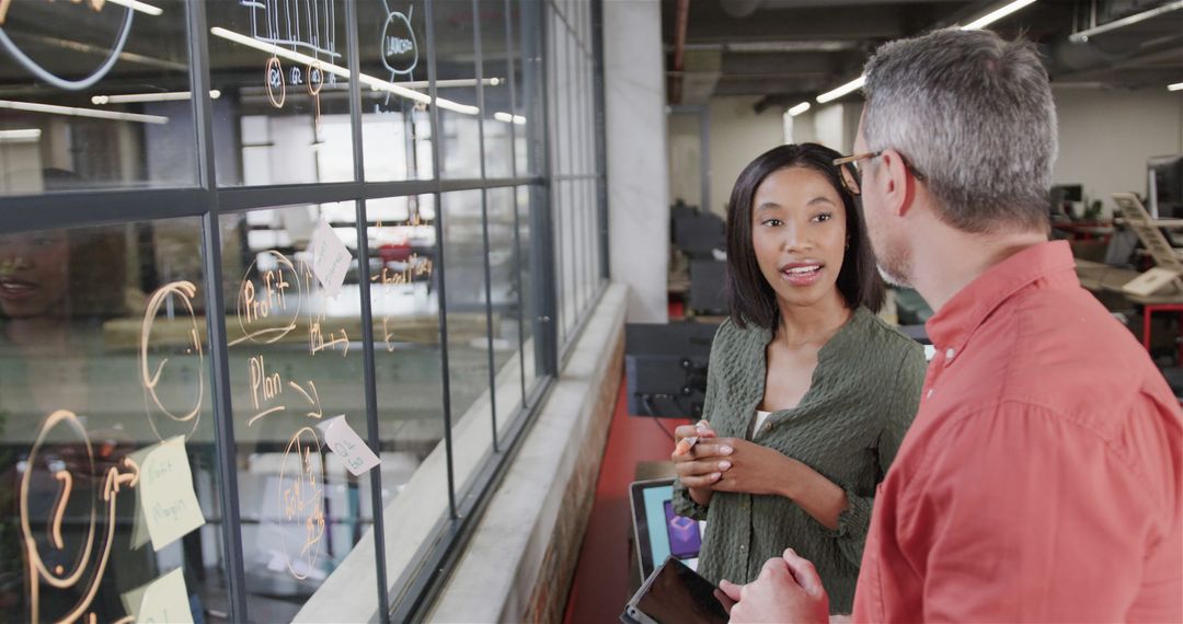 Diverse Colleagues Brainstorming with Tablet and Glassboard