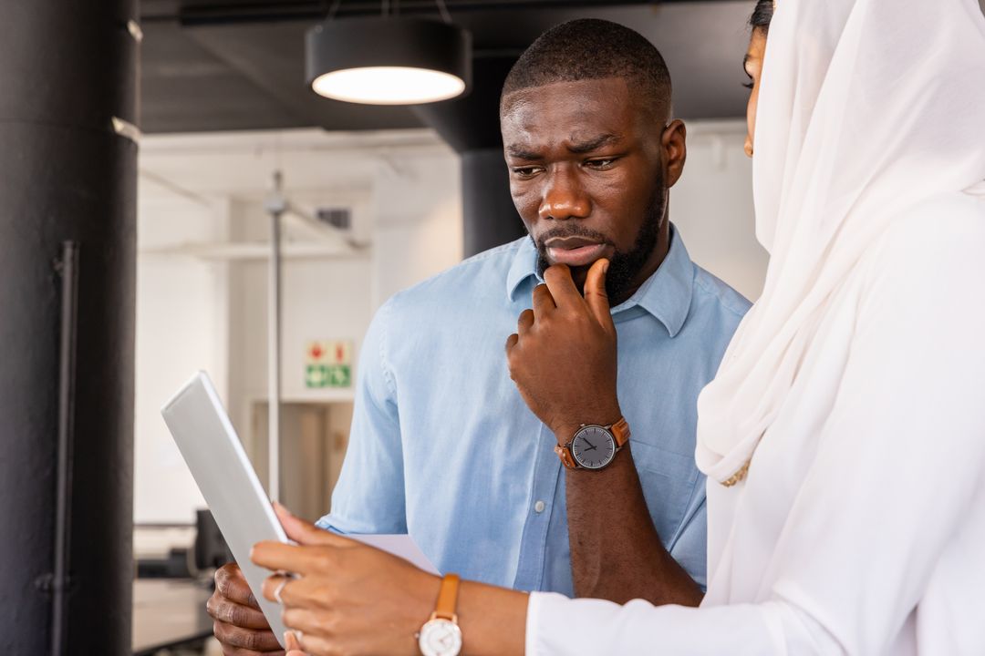Diverse Coworkers Reviewing Tablet in Open-Plan Office