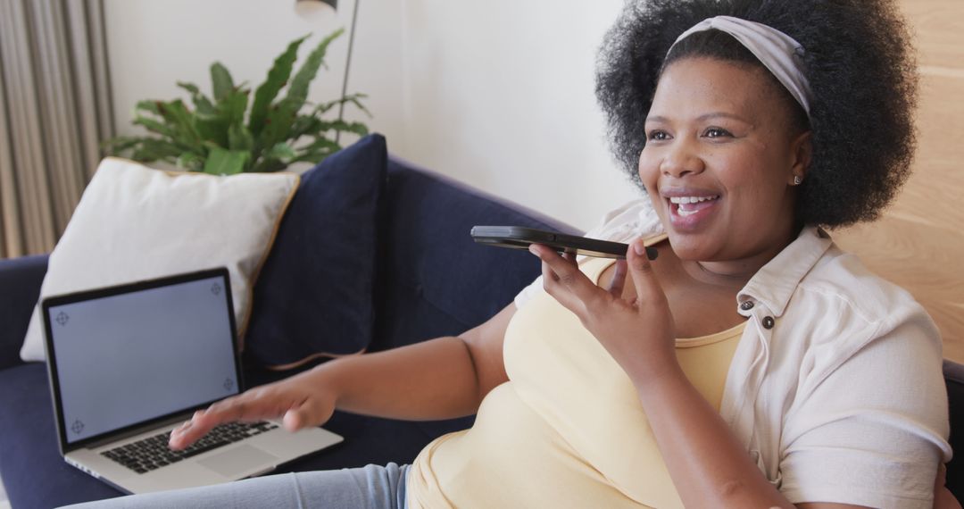 Joyful Plus Size Woman Using Smartphone with Laptop at Home