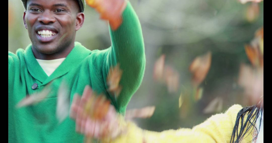 Happy Man Playing with Autumn Leaves in Green Sweater - Free Images, Stock Photos and Pictures on Pikwizard.com