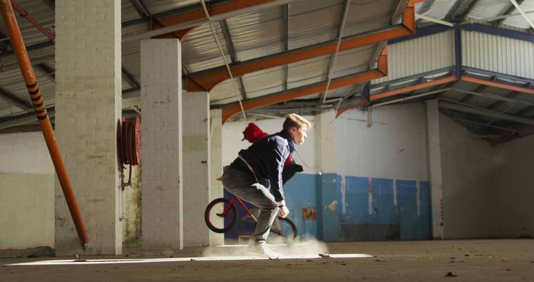 Young Man Wiping Out on Bike Inside Abandoned Warehouse - Free Images, Stock Photos and Pictures on Pikwizard.com