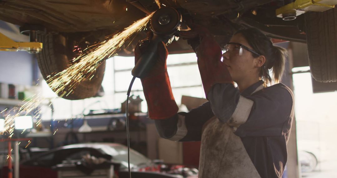 Caucasian Female Mechanic Grinding in Busy Workshop