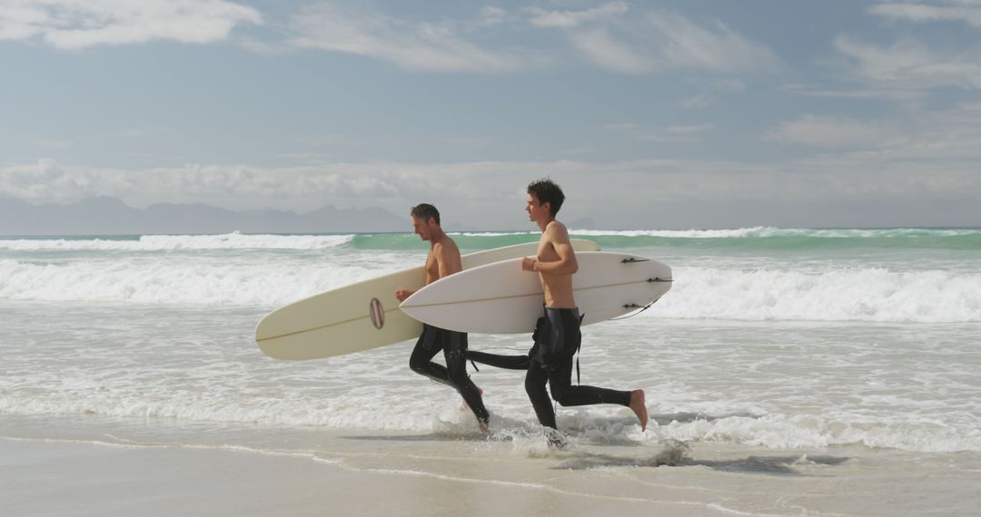 Surfers Running to Ocean with Surfboards on Beach - Free Images, Stock Photos and Pictures on Pikwizard.com