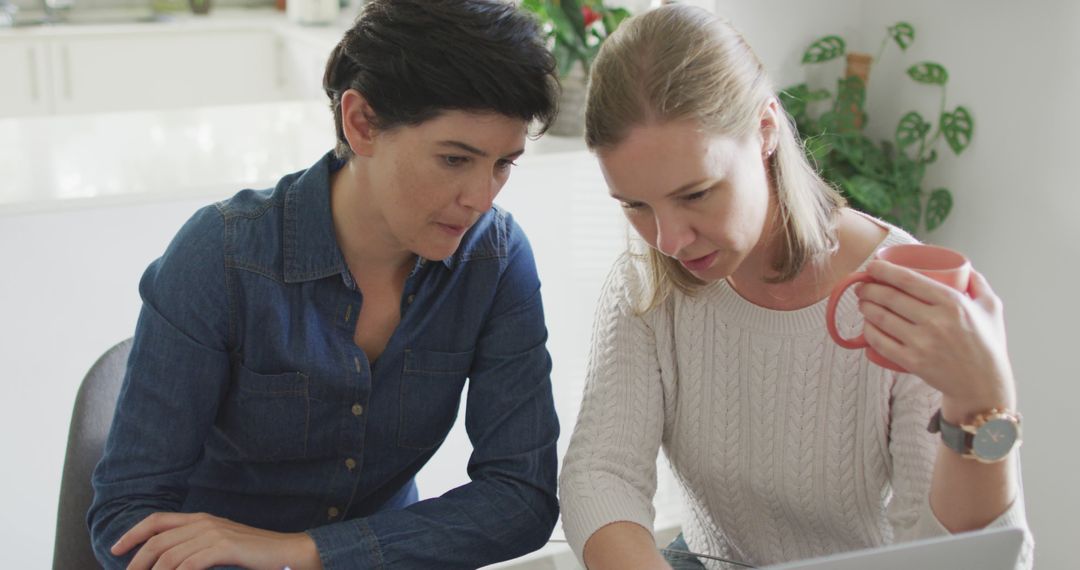 Caucasian lesbian couple smiling while talking to each other at home - Free Images, Stock Photos and Pictures on Pikwizard.com